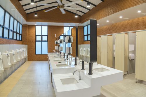 Image is of a public bathroom with several sinks and toilets, concept of Cooper City plumbing services