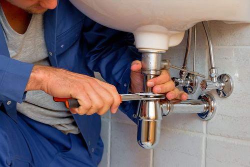 Image is of a plumber working on a sink, concept of boca Raton commercial plumbing